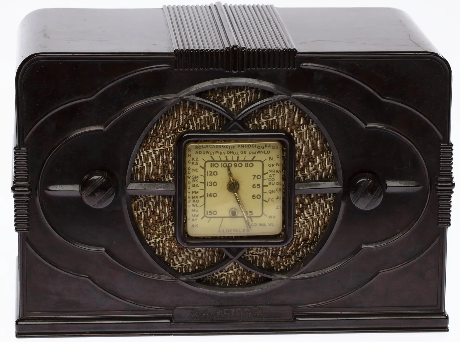 A small chocolate-brown bakelite radio, its front moulded in scallops round two overlapping circles over a woven speaker cloth, with a square ivory dial in the middle and a knob each side.